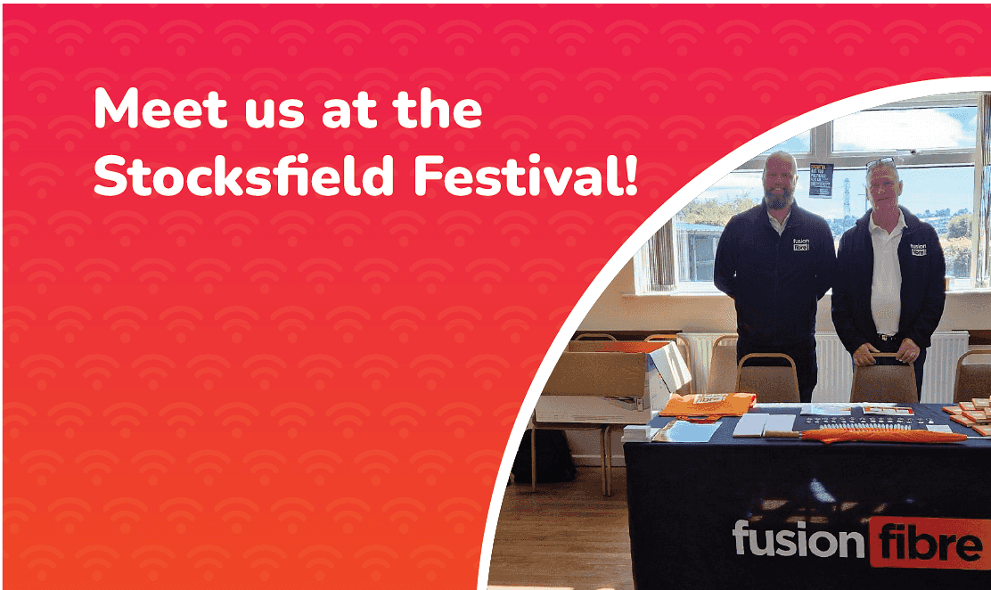 Two Fusion Fibre Group team members standing behind a branded table at the Stocksfield Festival, with a banner that reads “Meet us at the Stocksfield Festival!” on a red background.