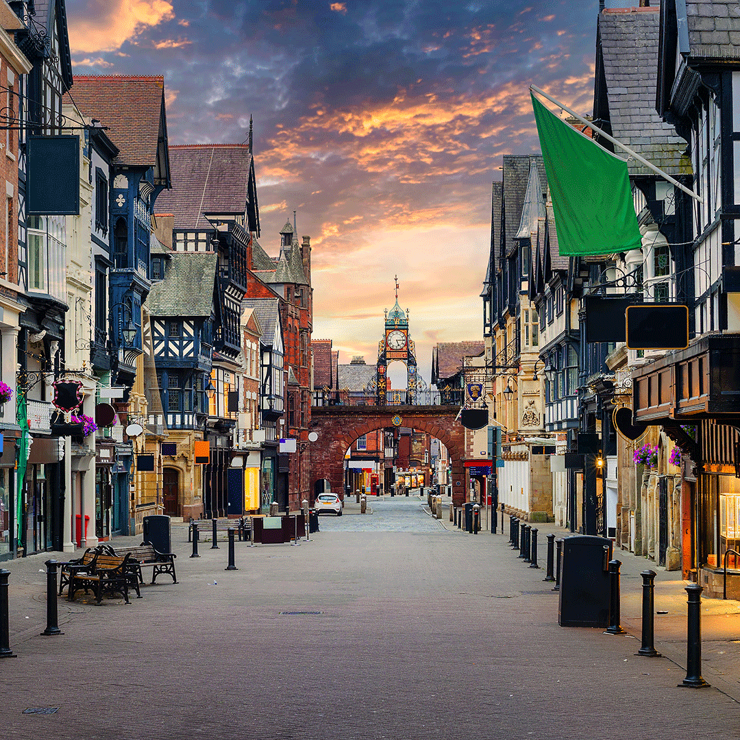 Chester city centre in Cheshire with historic Tudor-style buildings and the Eastgate Clock at sunset.